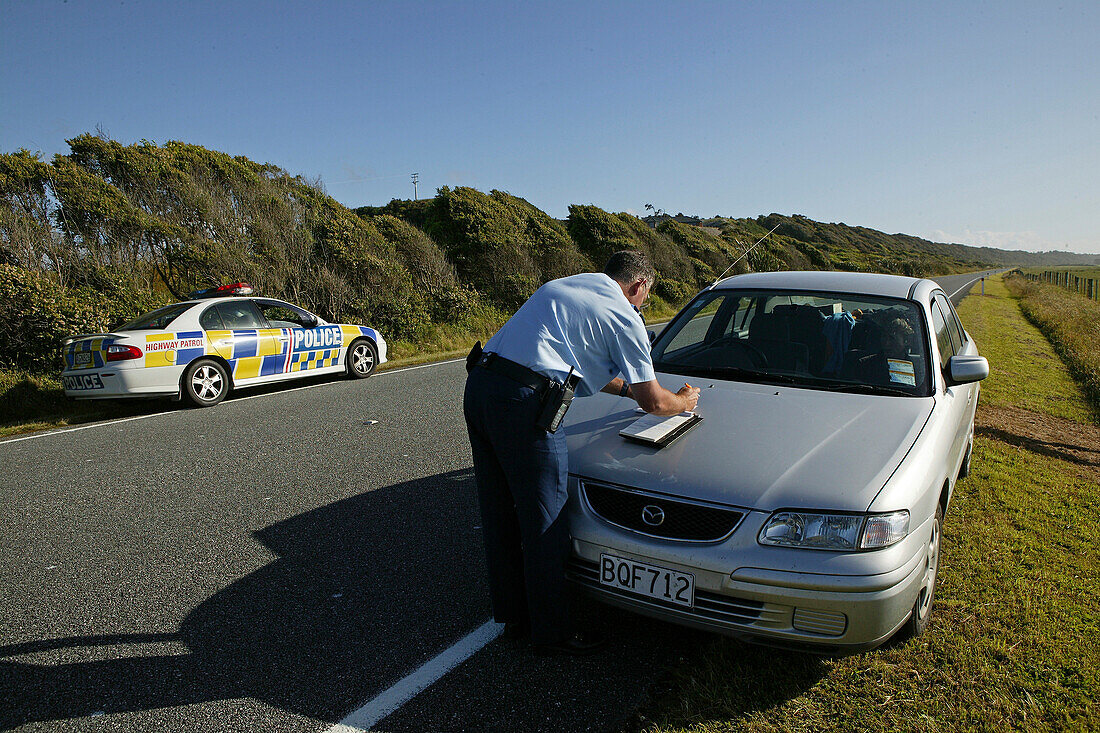 Policeman writes a speeding ticket, New Zealand policeman writing a speeding ticket on west coast Highway 6, South Island, Knoellchen