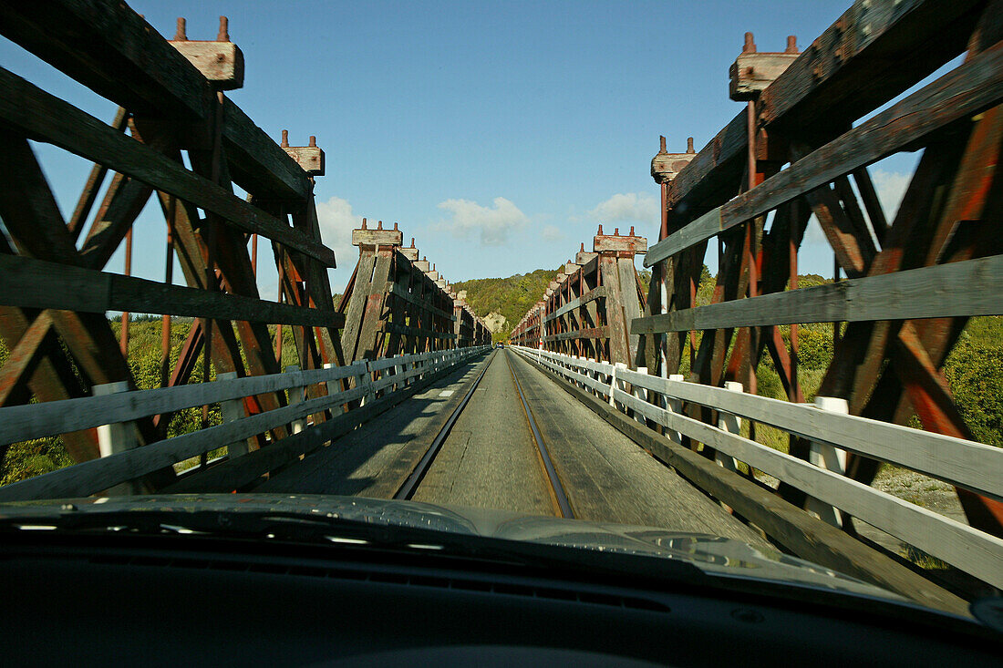 Holzbrücke im Sonnenlicht, Eisenbahn und Strassenverkehr teilen sich die schmale Brücke, Westküste, Südinsel, Neuseeland, Ozeanien
