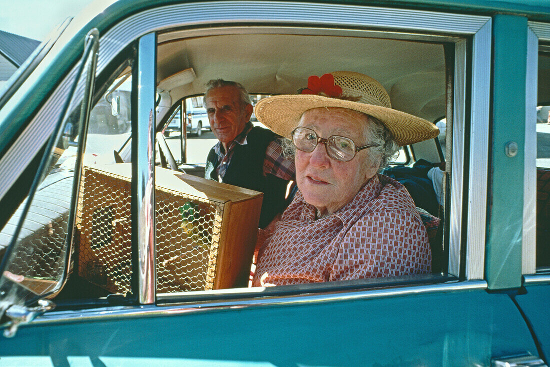 Old couple with budgie in vintage car, South Island, New Zealand