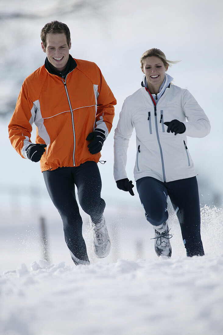 Young couple running on snow