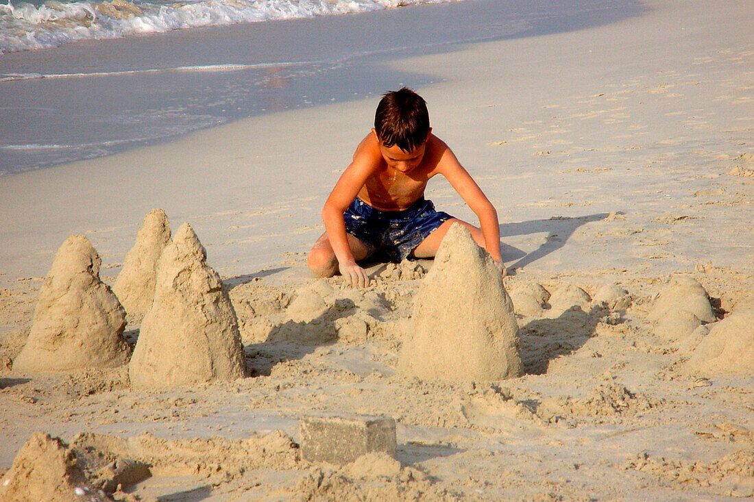 Junge baut eine Sandburg am Strand, Dubai, VAE, Vereinigte Arabische Emirate, Vorderasien, Asien