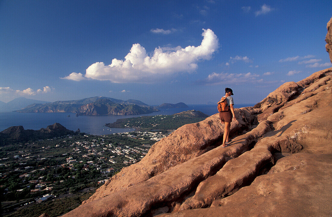 Woman hiking up Gran Cratere with view over Lipari, Vulcano, Aeolian Islands, Italy