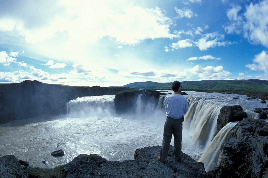 Mann betrachtet den Wasserfall, Godafoss, Norden, Island