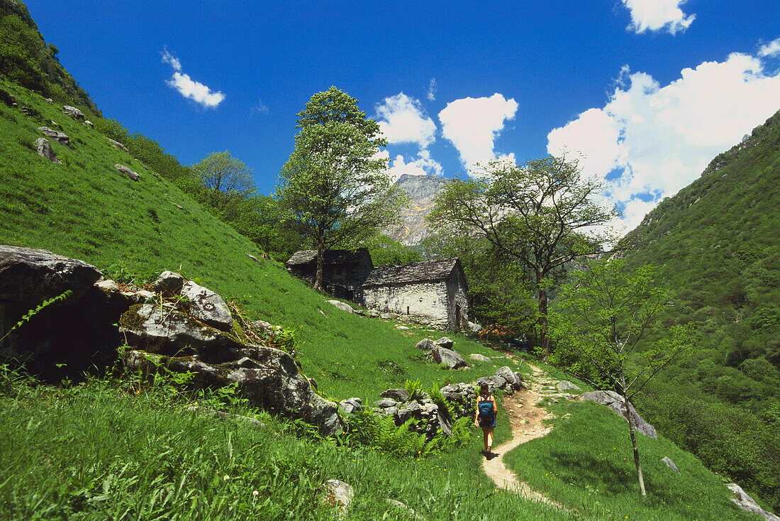 Female hiker walking on path through mountains, Lavertezzo, Verzasca, Ticino, Switzerland