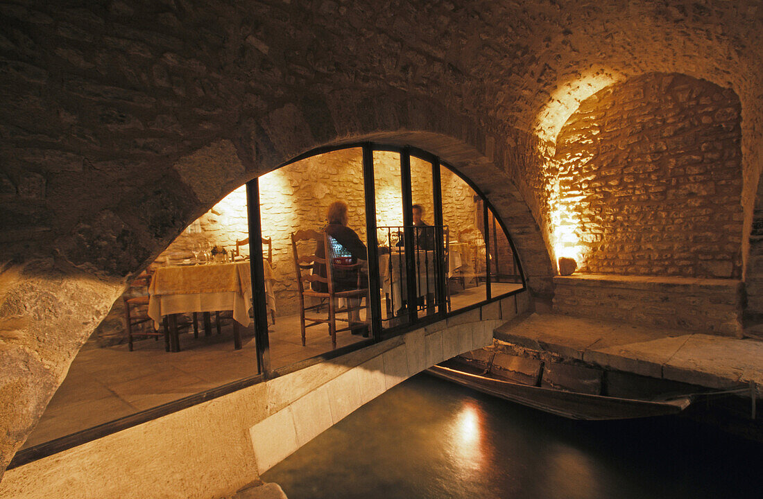 Blick aus einem Gewölbe auf Menschen im beleuchteten Restaurant La Prévote, Isle de la Sorge, Provence, Frankreich