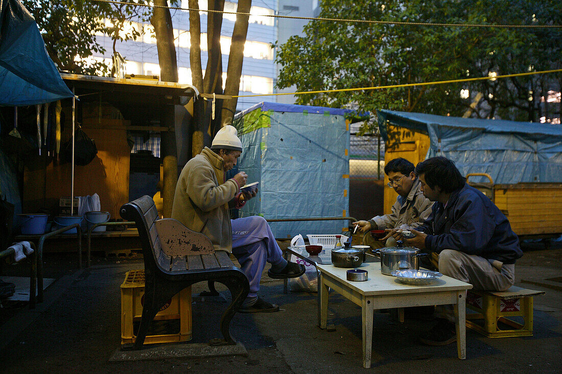 Homeless, living boxes in Tokyo-Shibuya, Japan, Homeless community on a car park roof in Shibuya, residents having dinner, self made shelter, architecture of cardboard boxes, plywood, blue fabric sheets Obdachlose, notdürftige Schutzbauten, Pappkarton-Arc