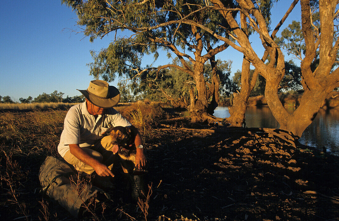 Swagman camps by a billabong with dog, Queensland, Australia