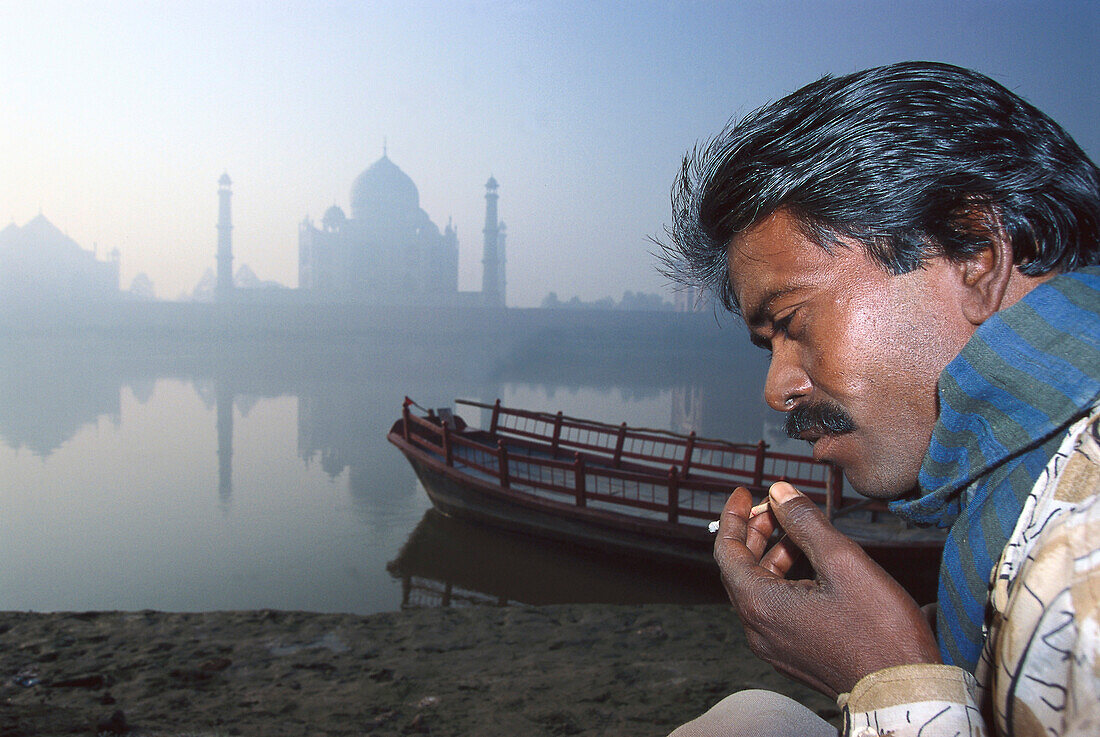 Fährmann vor Taj Mahal im Morgennebel mit Fluss Jamuna und Fährboot, Agra, Uttar Pradesh, Indien