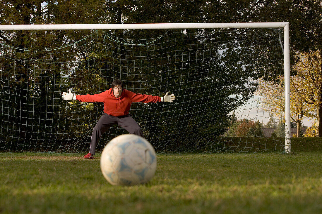Young goalkeeper awaiting penalty, arms outstretched