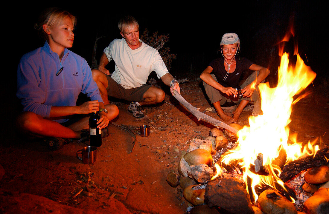 Three people sat around a campfire, Camping, Arizona, USA