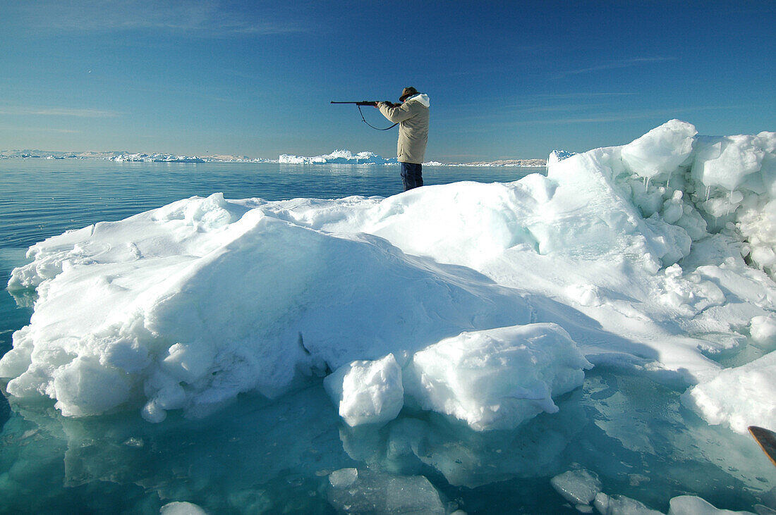 Ein Jäger mit Gewehr steht auf einer Eisscholle, Ilulissat, Grönland