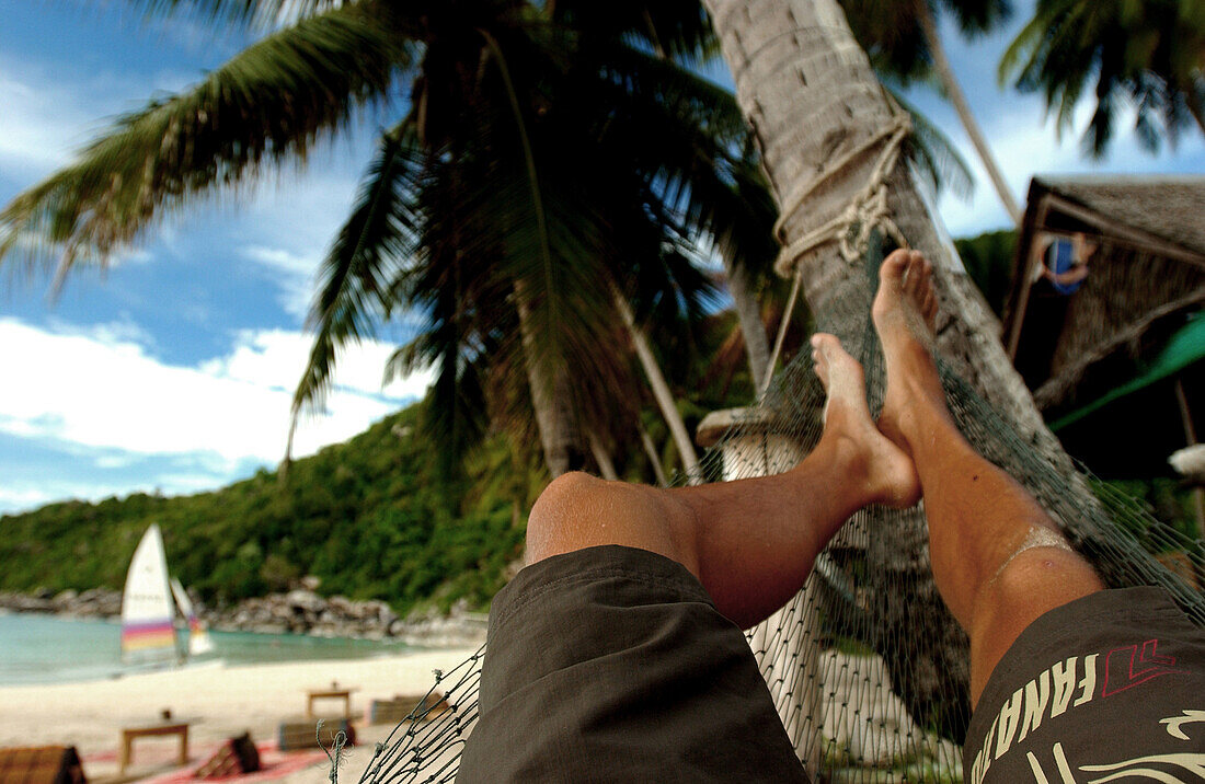 Man relaxing in a hannock on the beach, Koh Phangan, Thailand