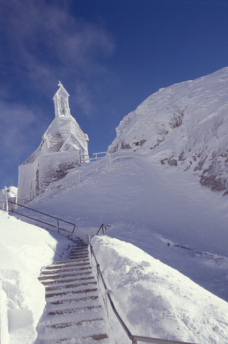 Staircase to snow covered chapel, Wendelstein Mtn., Upper Bavaria, Germany