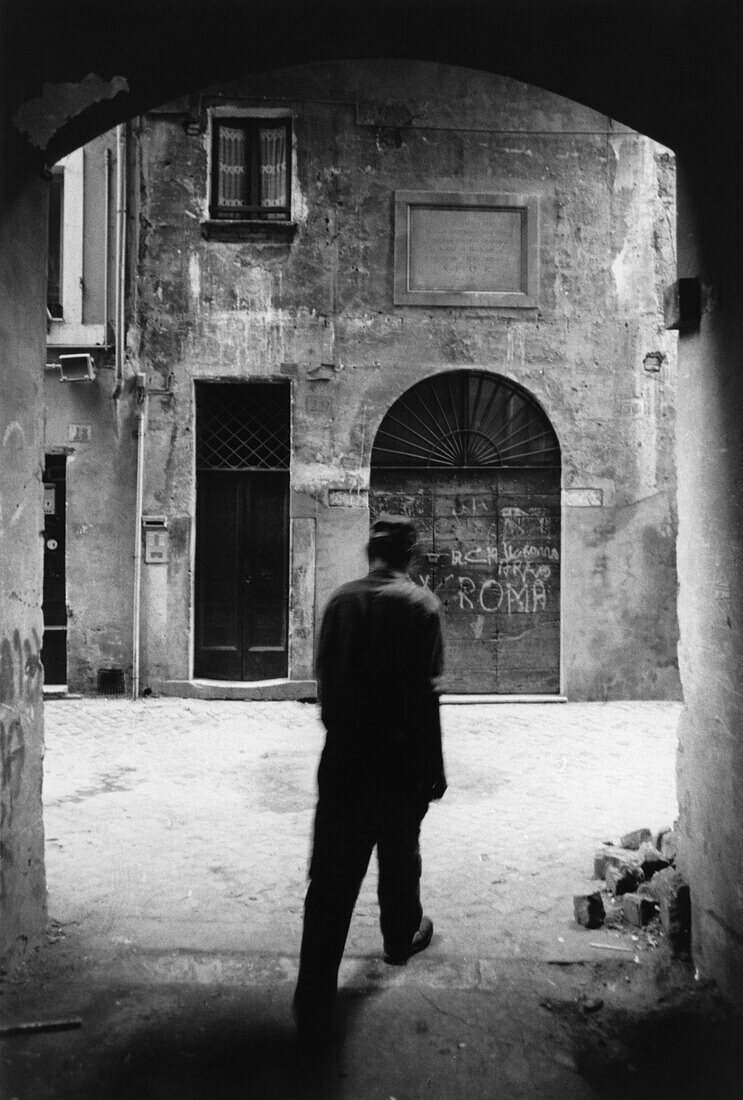 Man walking through a gate on the street, Rome, Italy