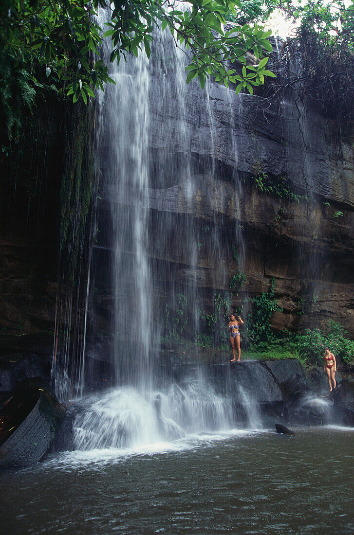 Two women showering under the waterfall, Shimba Hills National Reserve, Shimba, Kenya, Africa