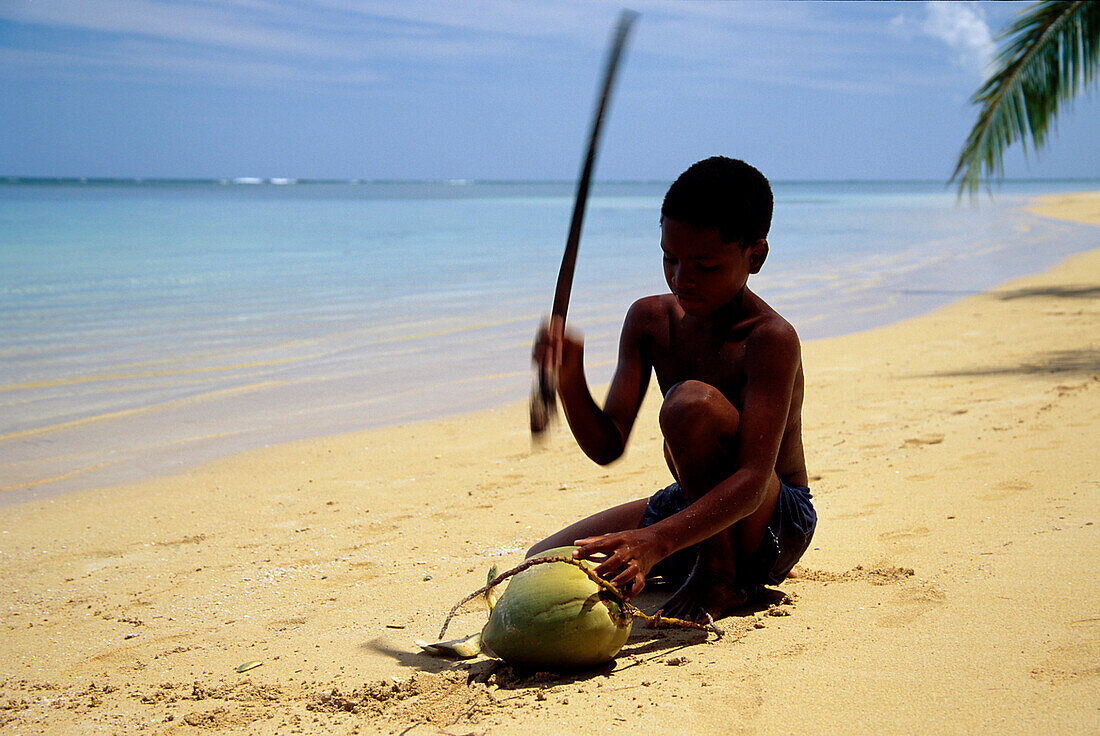 Junge mit Kokosnuss am Strand, Dominikanische Republik
