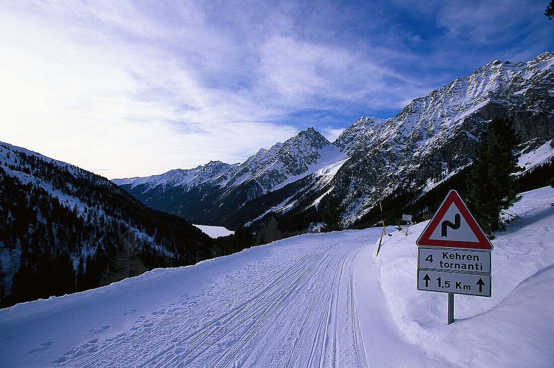 Verschneite Strasse und Verkehrsschild in den Bergen, Staller Sattel, Antholz, Pustertal, Südtirol, Italien, Europa