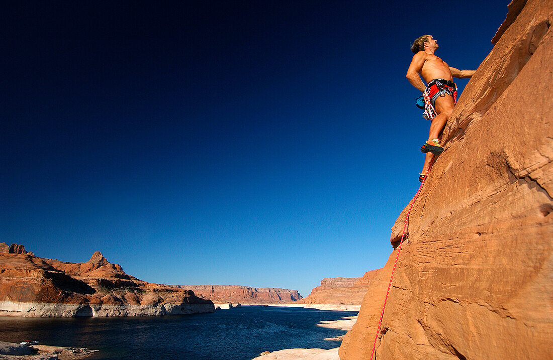 Man climbing up rock face, Lake Powell, Arizona, USA