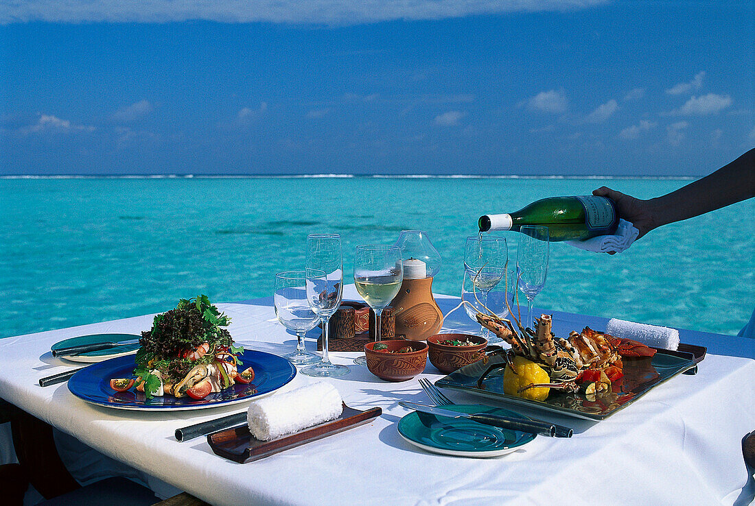 A table is laid on the waterfront in the sunlight, Four Seasons Resort, Kuda Hurra, Maledives, Indian Ocean
