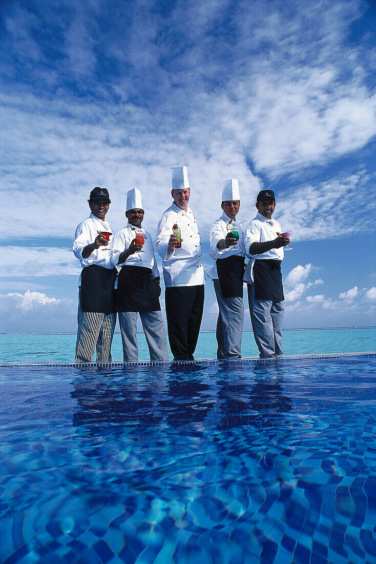 Cooks and waiters at the pool under clouded sky, Four Seasons Resort, Kuda Hurra, Maledives, Indian Ocean