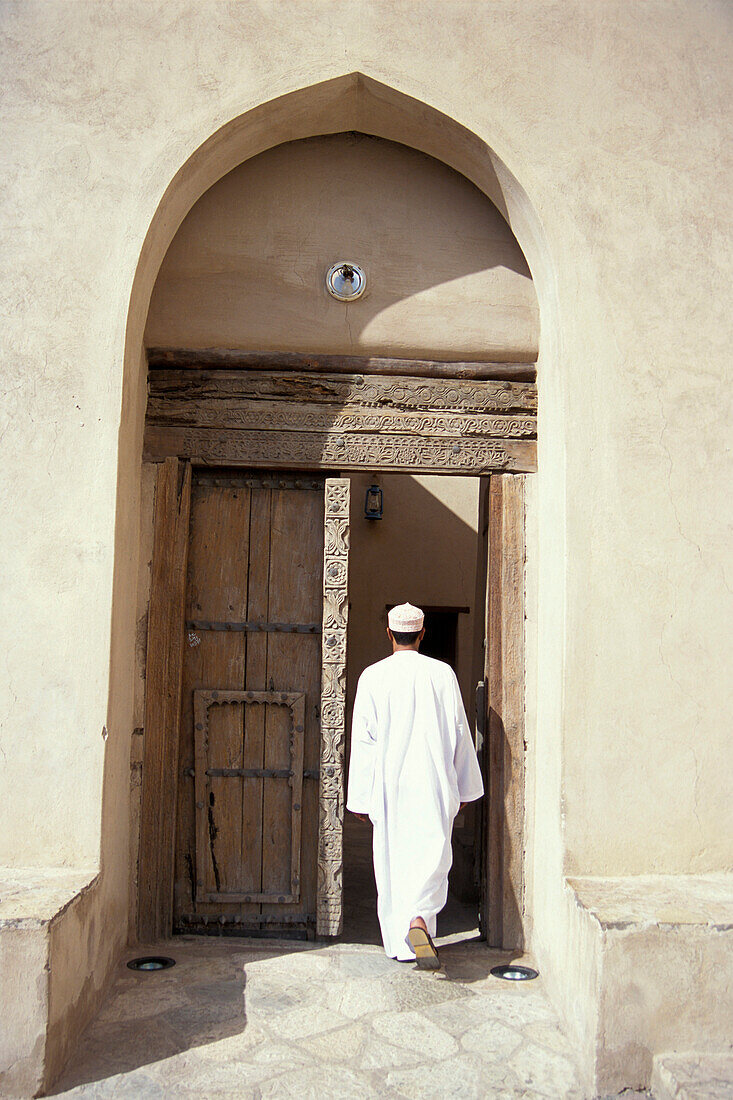 Ein Mensch geht durch eine Tür in das Fort, Nizwa, Oman