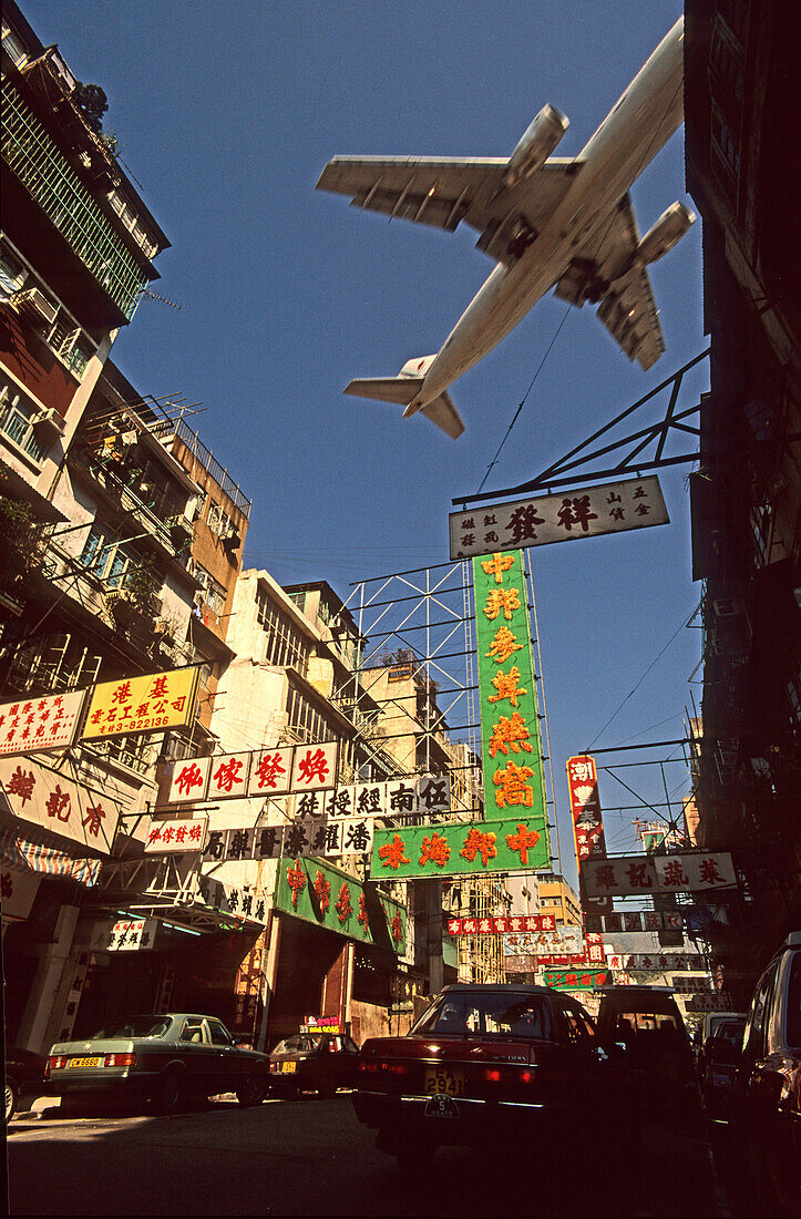 Aircraft flying above built-up area Kowloon, before opening airport on Lantau, Hong Kong, China