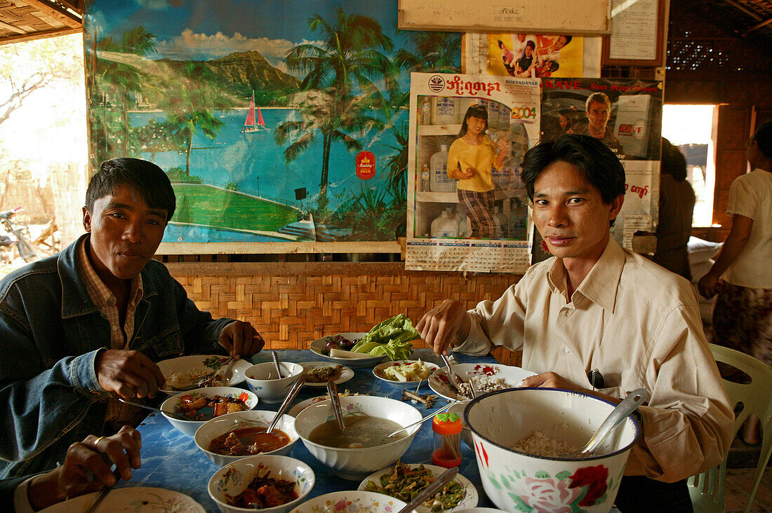 Burmese table of food, Maenner essen typisch Burmesisch, mit viele Teller am Tisch, typical roadside restaurant in Bagan, many dishes