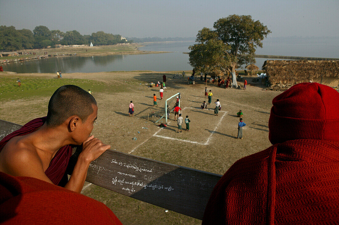 Monks watch football match from U Bein bridge, Moenche beobachten Fussballspiel von der U Bein Bruecke, Amarapura bei Mandalay