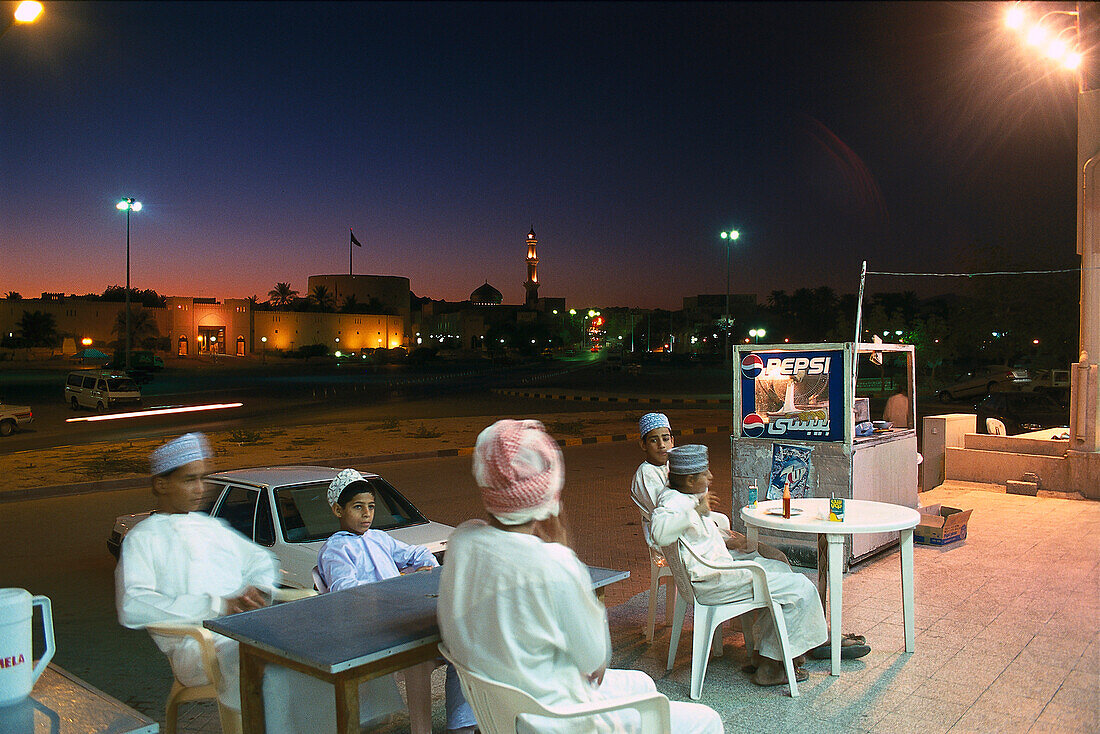 People sitting in a sidewalk cafe in the evening, Nizwa, Oman