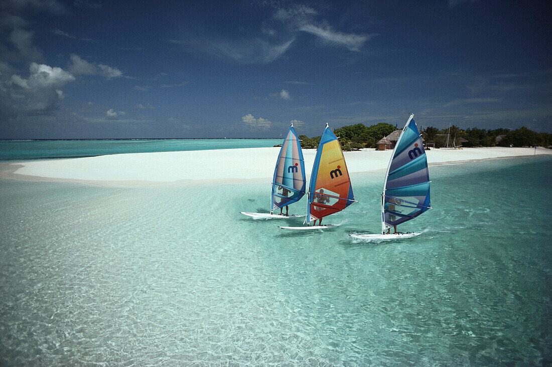 Drei Windsurfer vor dem Strand des Reti Raa Resort, Malediven, Indischer Ozean