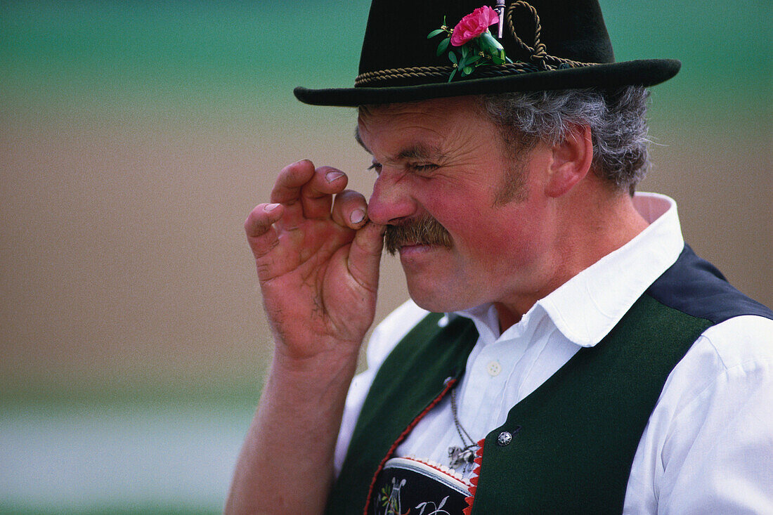 Man in traditional clothes taking snuff, Chiemsee Lake, Upper Bavaria, Germany
