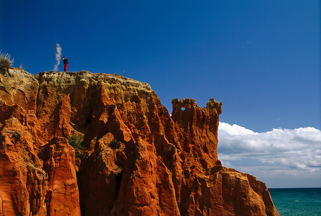 Golfer swinging on rugged terrain, Algarve, Portugal, low angle view