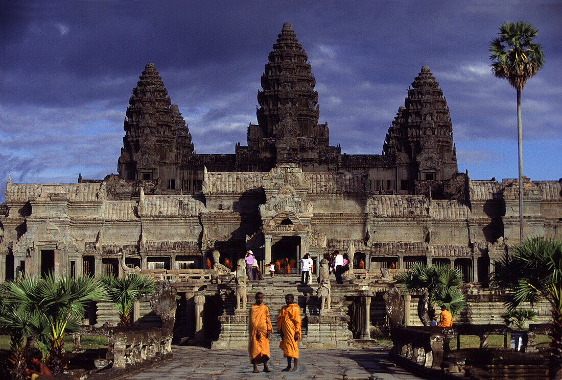 Monks in front of the temple Angkor Wat under clouded sky, Siem Raep, Cambodia, Asia