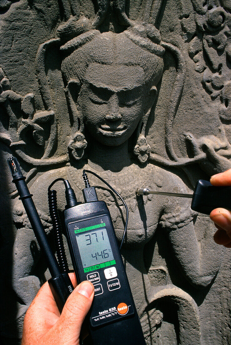 Ein Mann misst die Temperatur eines Reliefs, Angkor Wat, Siem Raep, Kambodscha, Asien