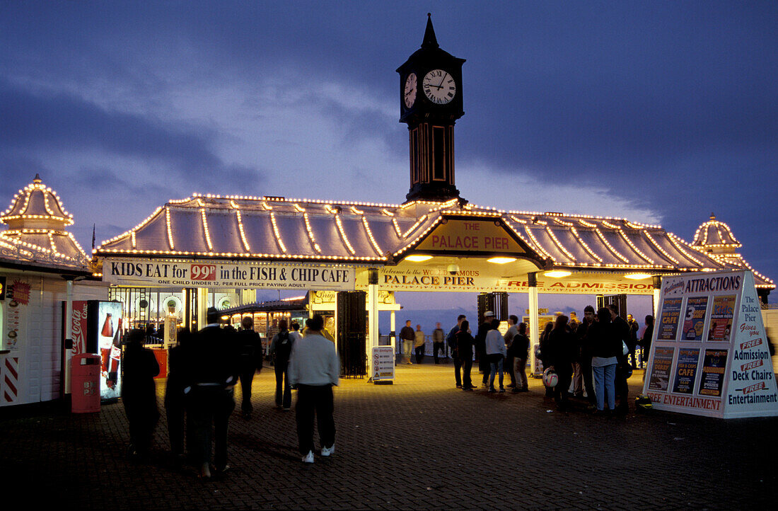 Menschen bei Nacht am beleuchteten Palace Pier, Brighton, Sussex, England