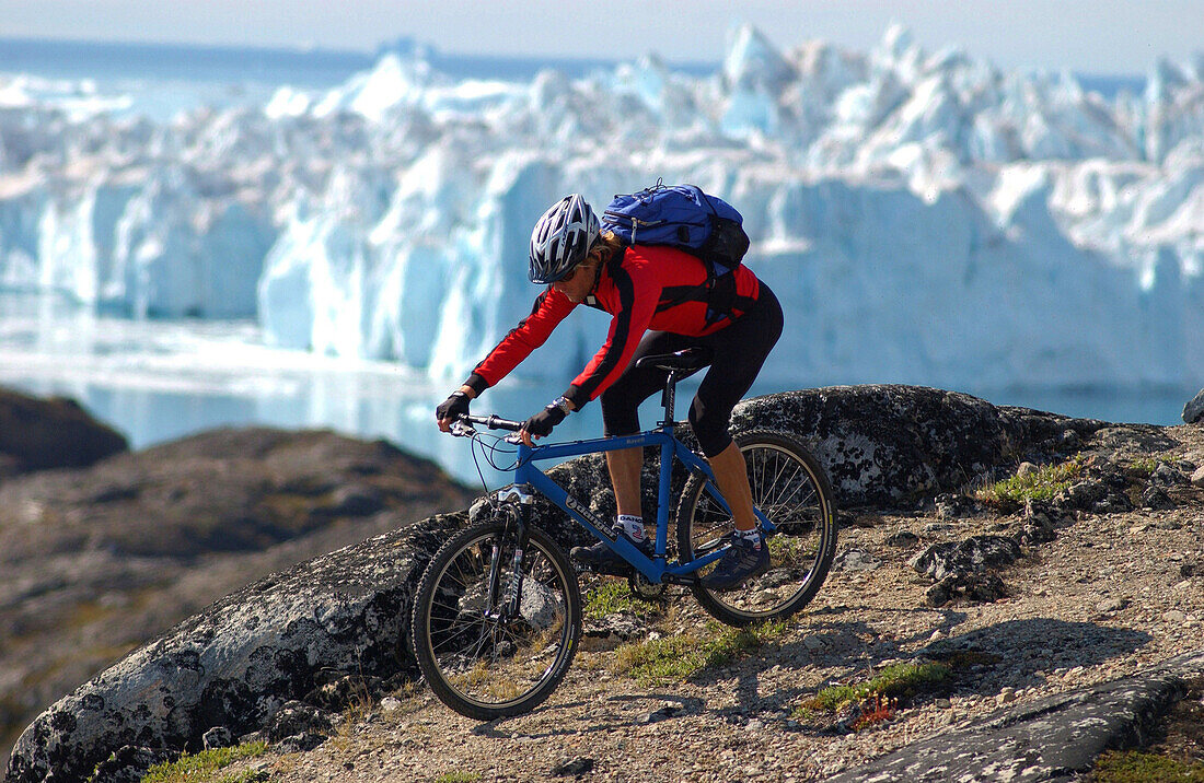 Ein Mann beim Mountainbiken über Felsen, Jakobshavn, Ilulissat, Grönland