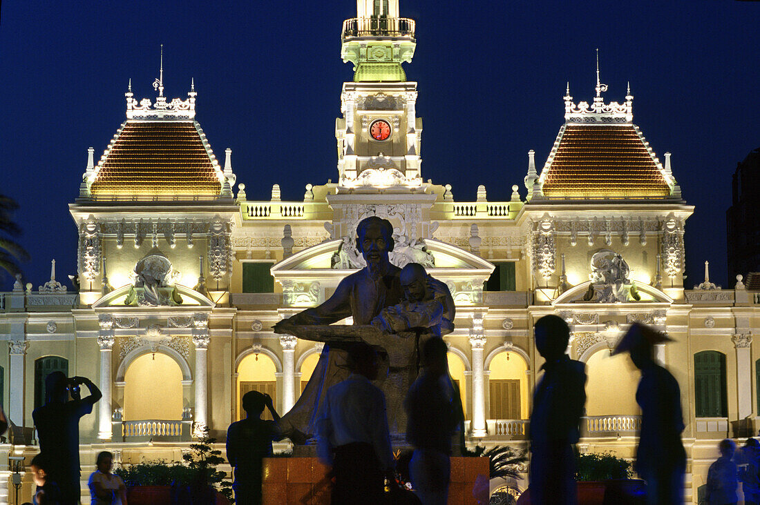 Statue und Menschen vor dem beleuchteten Rathaus bei Nacht, Ho Chi Minh City, Vietnam, Asien