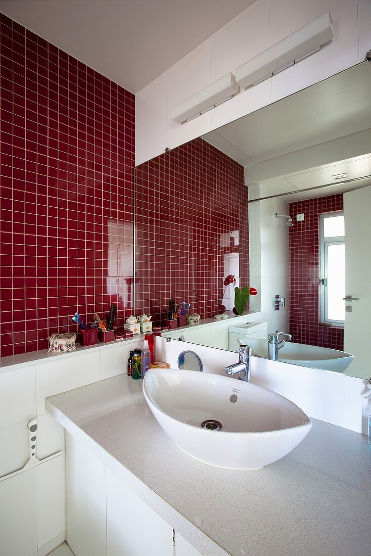 A red-tiled wall in a bathroom with a view of the basin