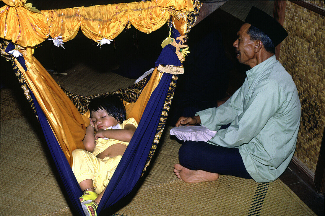 Mann singt ein Kind in den Schlaf, Penang, Malaysia, Asien
