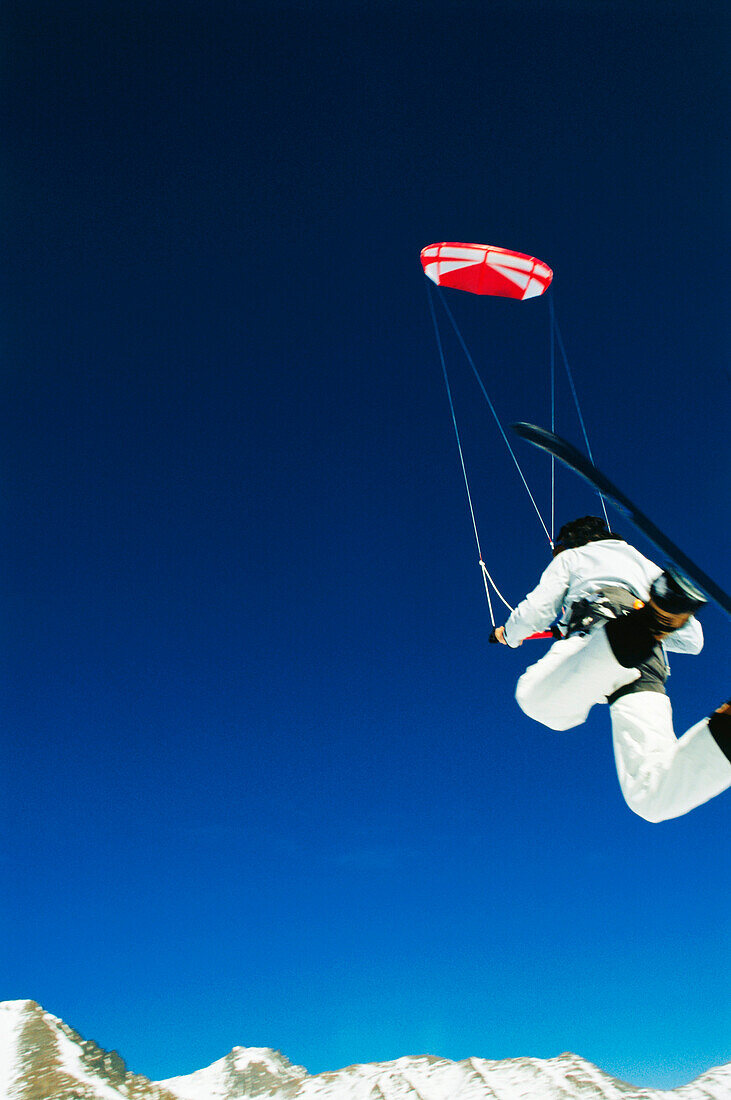 Mann springt beim Snowkiting, Lermoos, Lechtaler Alpen, Tirol, Österreich