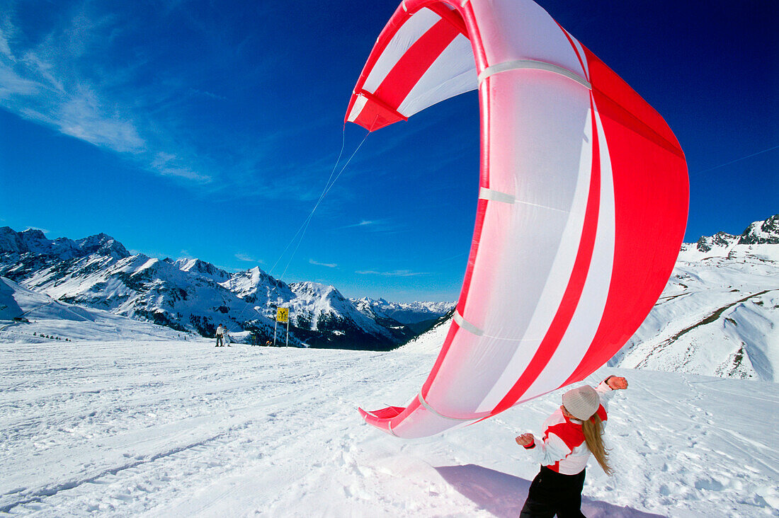Junge Frau hält Lenkdrachen zum Snowkiting, Lermoos, Lechtaler Alpen, Tirol, Österreich