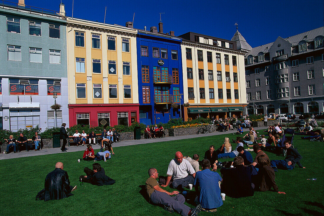 Row of colourful houses, people sitting on the grass, Reykjavik, Island