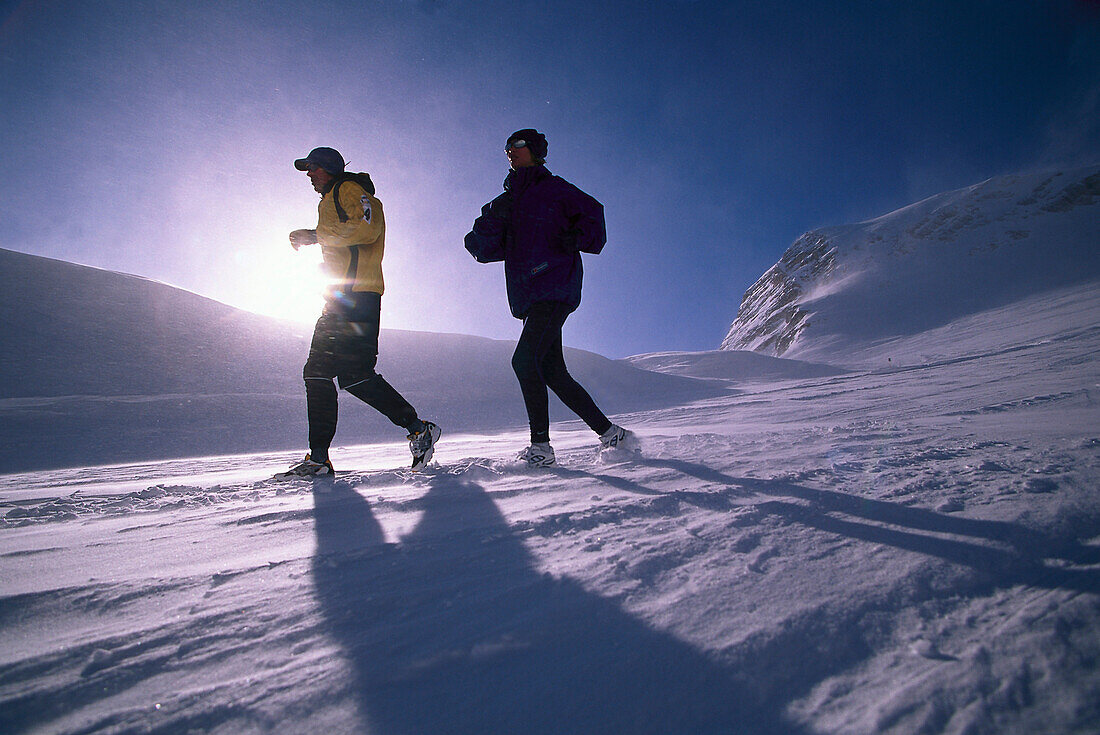 Ein Paar joggt auf verschneitem Weg, Österreich