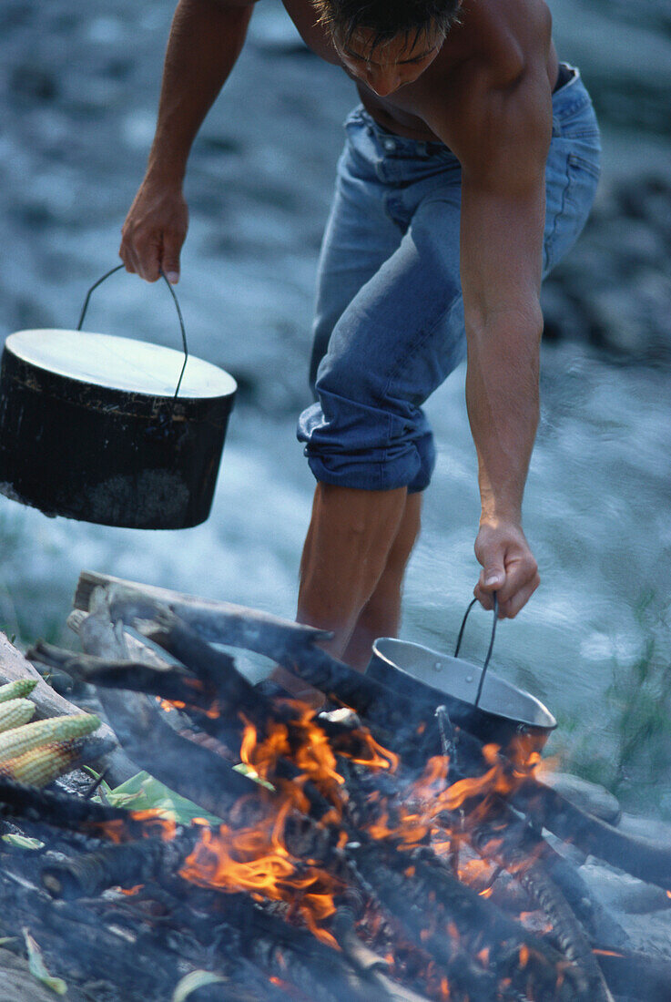 Mann beim Kochen in der Wildnis, Oberbayern, Deutschland