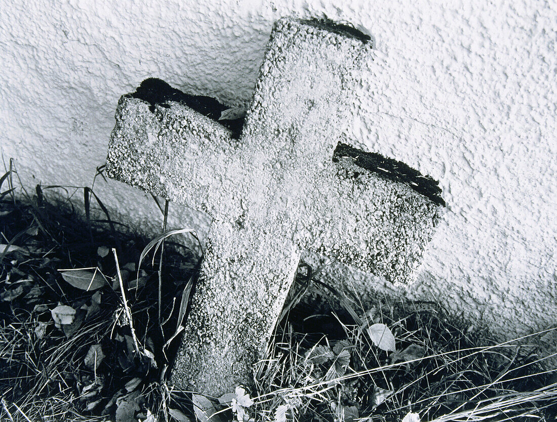 Ein Steinkreuz lehnt an einer Mauer