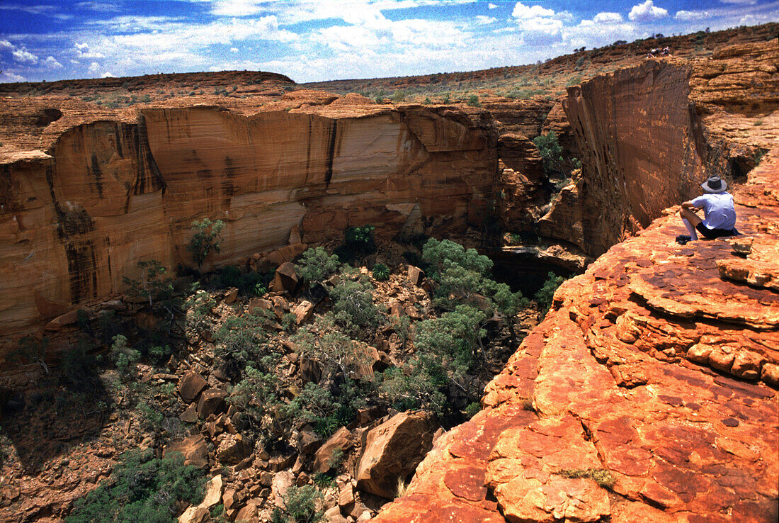 A man sitting at the edge of Kings Canyon, Kings Canyon National Park, Northern Territory, Australia