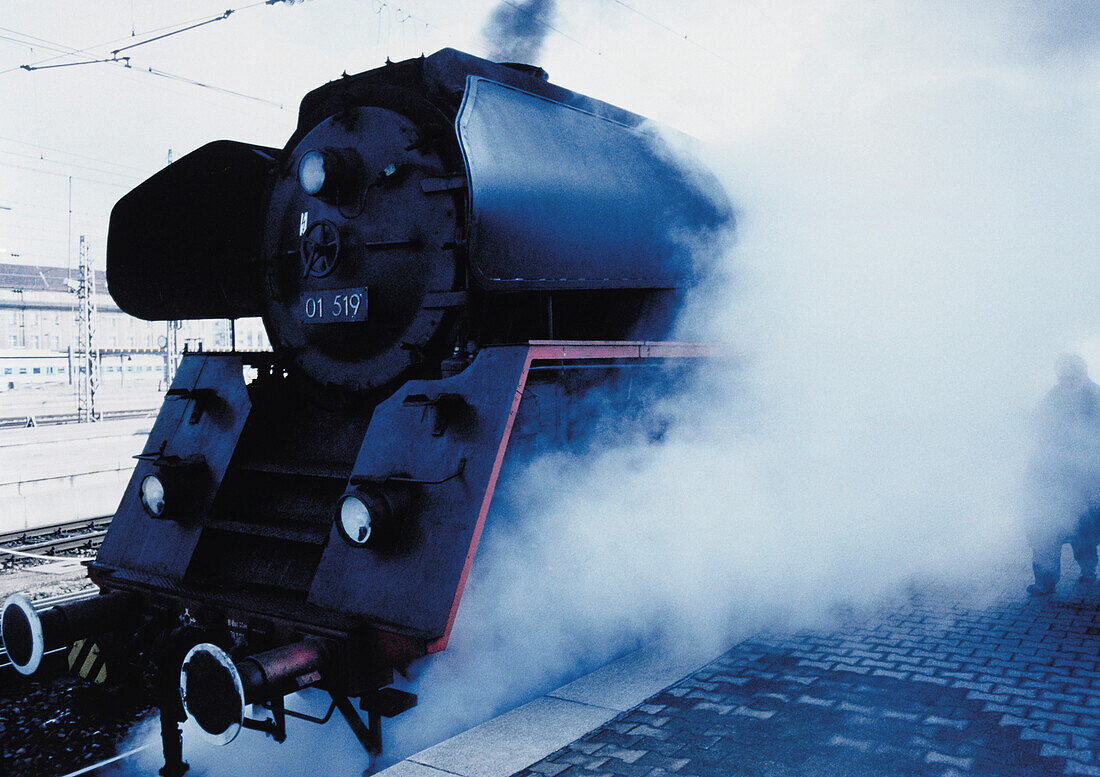 Dampfende Lokomotive steht am Bahnsteig