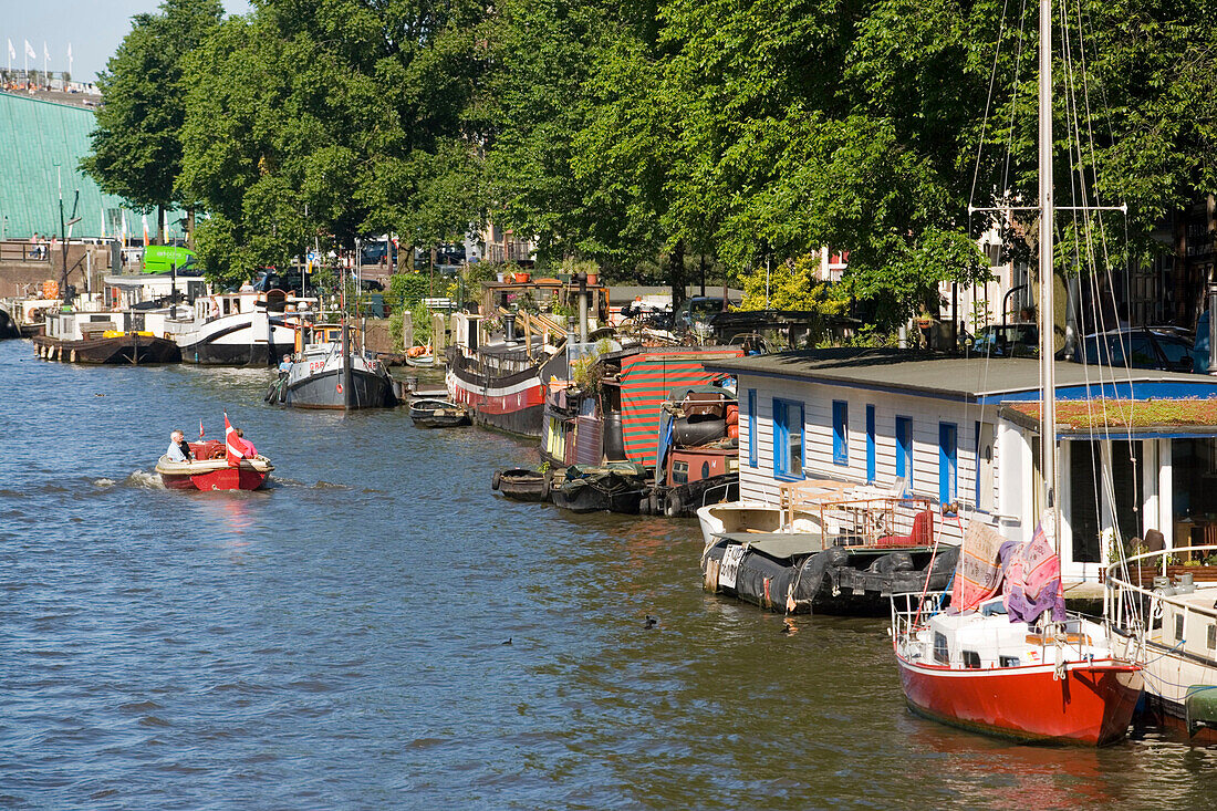 Leisure Boats, Oude Schans, A small leisure boat passing house boats on Oude Schans, Amsterdam, Holland, Netherlands