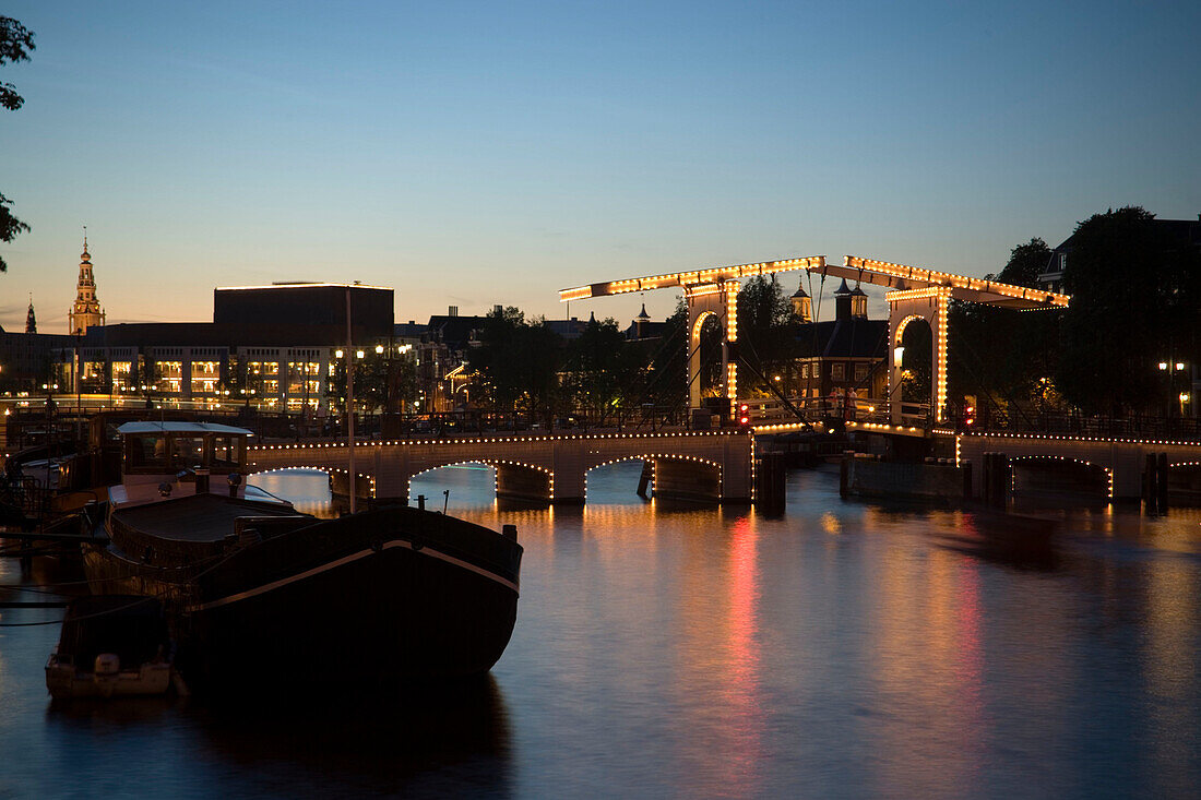 Boats, Magere Brug, Amstel, View over illuminated Magere Brug Skinny Bridge, to Stopera and Zuiderkerk at night, Amsterdam, Holland, Netherlands