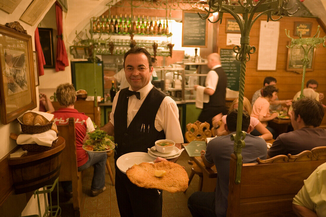 Waiter serving giant Viennese Schnitzel at Restaurant Figlmueller, Vienna, Austria
